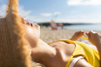 Djevojka u žutom toplesu se sunča na plaži.