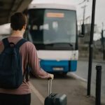 Mlada osoba stoji ispred autobusa spreman na odlazak.