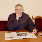 Svećenik fra Vjenceslav Janjić sjedi za stolom i čita novine.