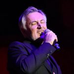 Popularni hrvatski pjevač Škoro u krupnom planu, drži mikrofon.