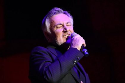 Popularni hrvatski pjevač Škoro u krupnom planu, drži mikrofon.