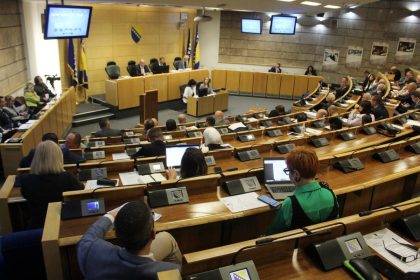 Zasjedanje Doma naroda Parlamenta Federacije BiH u polukružnoj sali, s delegatima za radnim mjestima i govornicom na sredini.