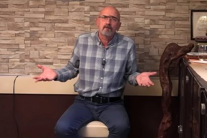 Urednik i voditelj emisije Defter hefte u voditeljskoj situaciji sjedi u studiju u kariranoj košulji sa raširenim rukama.