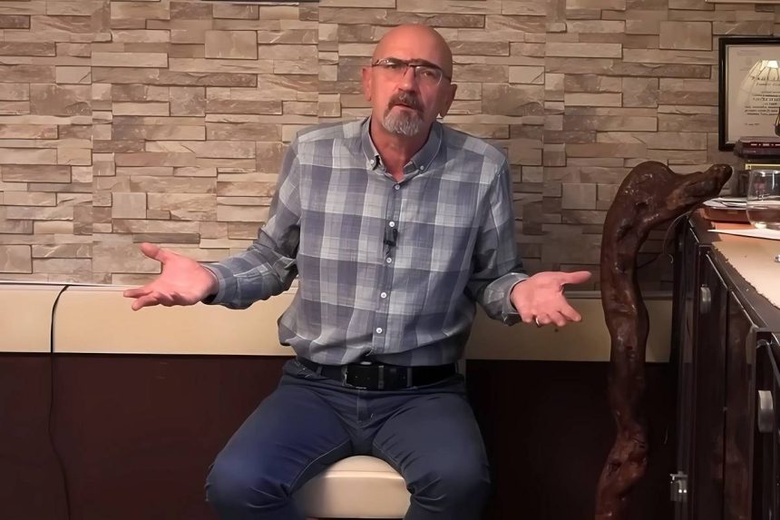 Urednik i voditelj emisije Defter hefte u voditeljskoj situaciji sjedi u studiju u kariranoj košulji sa raširenim rukama.