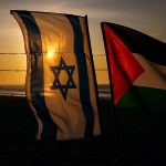Zastave Izareale i Palestine jedna pored druge u pozadini sunce na zalasku.