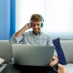 Osoba s laptopom i slušalicama koristi Windows 11 u opuštenom kućnom okruženju, simbolizirajući pristupačnost novog Copilota.