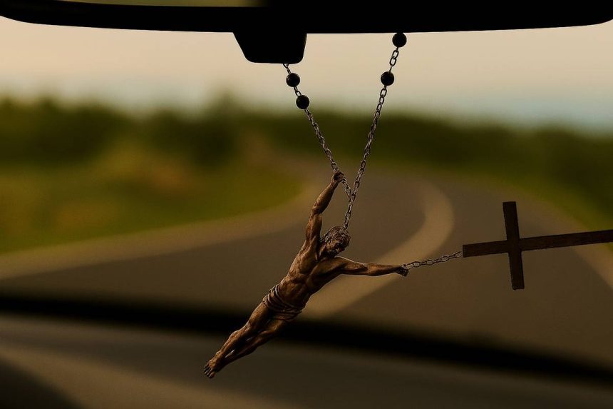 Krunica visi s retrovizora automobila, nagnuta zbog zavoja u vožnji. Isus, prikazan kao stvaran ljudski lik, otkinut je s križa i objeručke se drži za krunicu iznad križa, kao da ga inercija pokušava odbaciti. U pozadini se kroz vjetrobransko staklo vidi zamućena zavojita cesta.