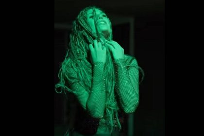 Mlada pjevačica Anami u zeleno osvijetljenom kadru iz glazbenog spota “Fobije”, s pletenicama i reflektirajućim kostimom.