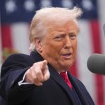 Američki predsjednik Donald Trump sa ispruženom rukom i kažiprstom. U pozadini američka zastava.