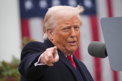 Američki predsjednik Donald Trump sa ispruženom rukom i kažiprstom. U pozadini američka zastava.