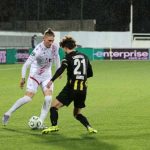 Dva nogometaša, u bijelom i crnom dresu nadmeću se za loptu.