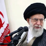 Ajatolah Hamnei. Ispred mikrofona, pored iranske zastave.