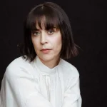 Profesorica Ana Mijić pozira u bijeloj košulji, iza tamna pozadina.