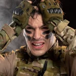 Vojnik u maskirnoj odori i sa crnim rukavicama drži se rukama za glavu.