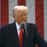 Predsjednik Trump iza mikrofona. U pozadini američka zastava.