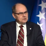 Christian Schmidt sjedi u studiu, pored njega zastava BiH.