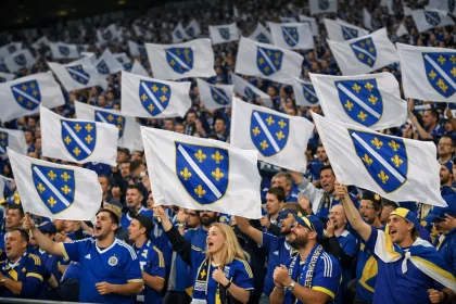 Navijači Bosne i Hercegovine u plavim dresovima mašu zastavama s ljiljanima na prepunim tribinama stadiona.